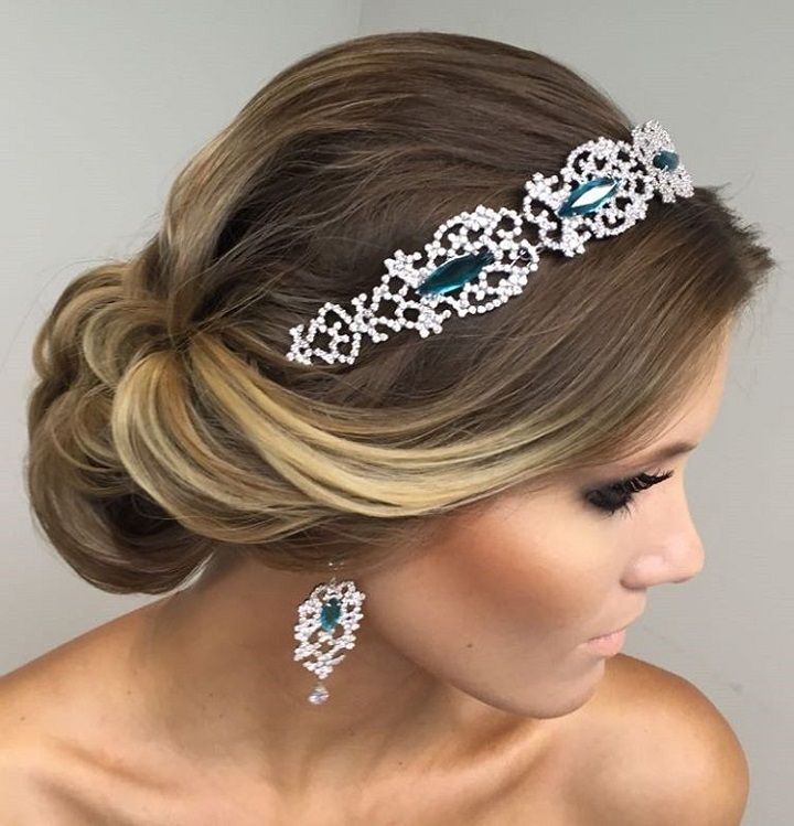 Messy bun finished with a beaded headband worn low across the forehead